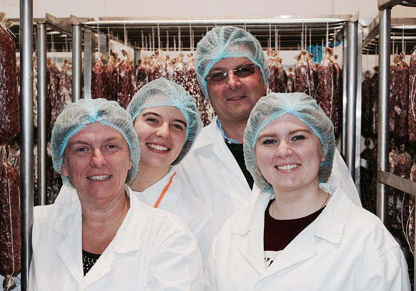 The Subissati team in their curing room at Roccastrada, salami hanging behind them